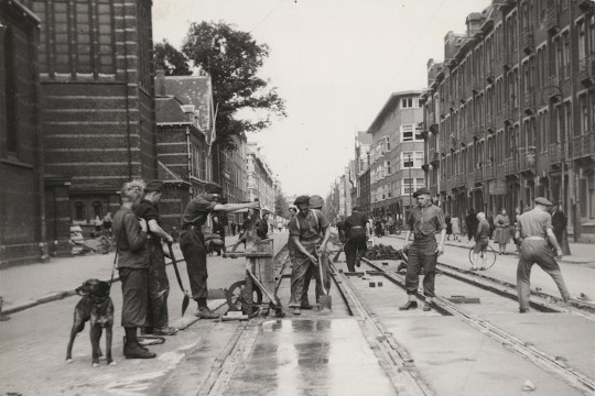 Canadese militairen herstellen de in de winter zwaar beschadigde trambanen in de Spaarndammerstraat